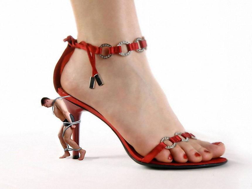 Duży czerwony pantofel kobiecy na nodze, do fleka przywiązany mężczyzna na łancuchach jako facet pod pantoflem.